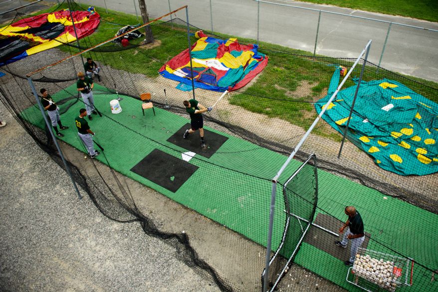 Lynchburg Hellcats players warm up in the batting tunnel. The practice areas are outside and along a road. (Drew Angerer/The Washington Times)