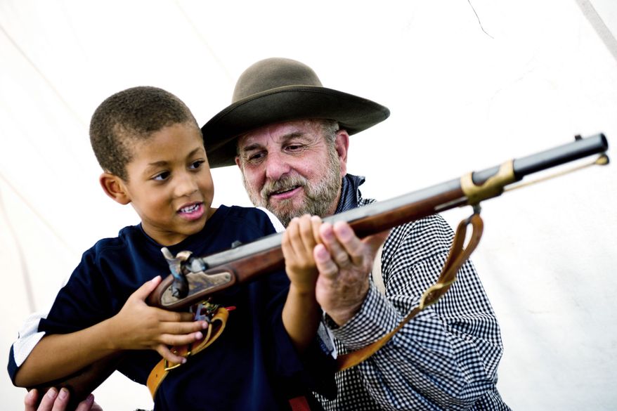 PHOTOGRAPHS BY DREW ANGERER/THE WASHINGTON TIMES
Tommy Phillips of Cookeville, Tenn., shows Malachi Reynolds, 5, of Fairfax how to hold his 1853 Enfield Gun at an encampment near the Manassas Museum on Thursday. "I just love talking to people about all this history," said Mr. Phillips. Dressed as Gen. Robert E. Lee for the weekend, Al Stone of Hinton, W.Va., stays in the shade under his tent to keep cool. Mr. Stone and his friends were camping out the entire weekend near the Manassas Museum to celebrate the 150th anniversary of the First Battle of Bull Run.