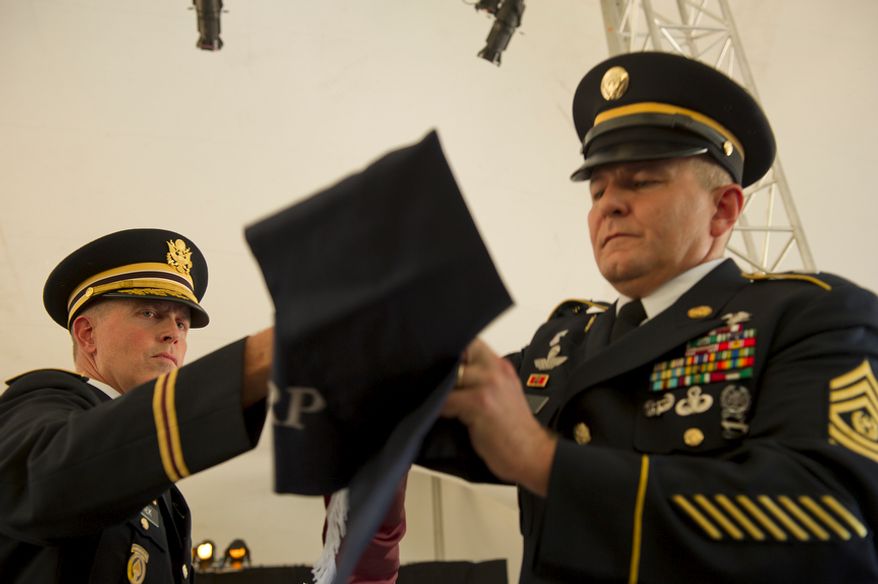 Col. William Schiek, left, and CSM Steven Craig retire (or "case") the Medical Center Brigade flag by rolling it up and covering it during a ceremony Wednesday, July 27, 2011 at Walter Reed Army Medical Center in Washington, D.C. The flags of the various medical units at Walter Reed were all retired during the ceremony as a means of transitioning from the Washington, D.C., facility to Ft. Belvoir and Bethesda Naval Medical Center. (Barbara L. Salisbury/The Washington Times)