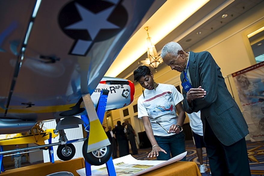 Dr. Donald Jackson, a bomber pilot and original Tuskegee Airman, prepares to sign a commemorative Tuskegee Airmen poster on the first day of the 40th Annual Tuskegee Airmen National Convention, at the Gaylord Hotel and Convention Center, in National Harbor, Md., Wednesday, Aug. 3, 2011. At left is convention volunteer Linze Greene, from Dallas. Her father and great uncle were both original Tuskegee Airmen. "You see these other guys here and it just does something wonderful for your human psyche," said Dr. Jackson, who is making his 6th trip to the convention this year. (Drew Angerer/The Washington Times)