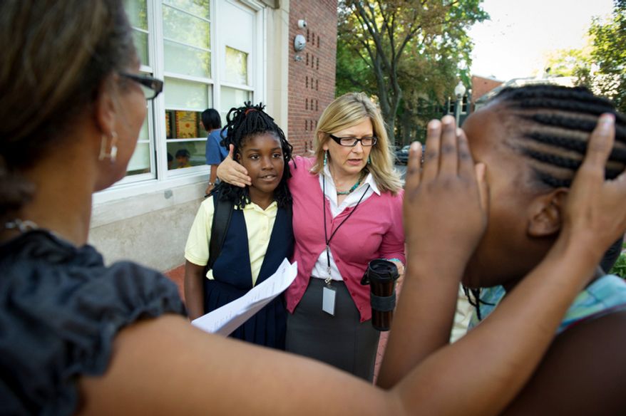 John Tyler Elementary School Principal Jennifer Frentress (right) puts her arm around student Monica Jackson, 10, (left) as students and their parents arrive for the first day of school. (Rod Lamkey Jr./The Washington Times)