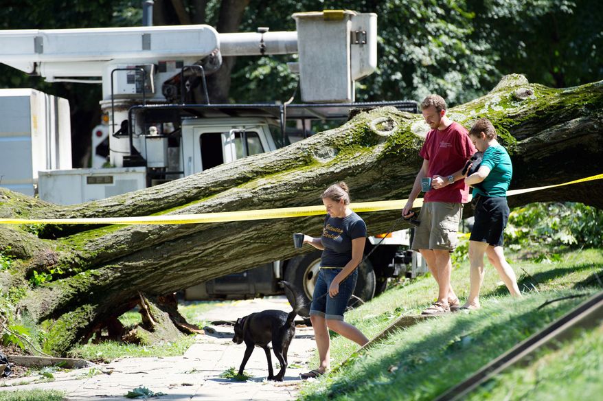 Neighbor Lisa Gelhaus (right) talks to D.C. resident Kevin Gibbons and his wife, Ashley Domm, on Sunday after a tree damaged the couple's apartment building in Glover Park. (Andrew Harnik/The Washington Times)