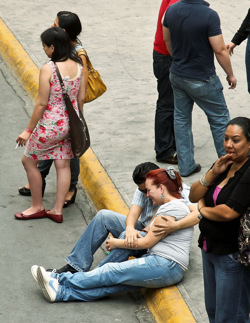 ASSOCIATED PRESS PHOTOGRAPHS
Mexico's President Felipe Calderon and his wife Margarita Zavala (above) attend a ceremony outside the Casino Royale on Friday, a day after a deadly assault claimed 52 lives. "It is evident that we are not faced with ordinary delinquents but by actual terrorists who know no boundaries," said Mr. Calderon. People wait for news about their relatives (below) outside the site where the government is testing DNA samples to match with the bodies of those killed.