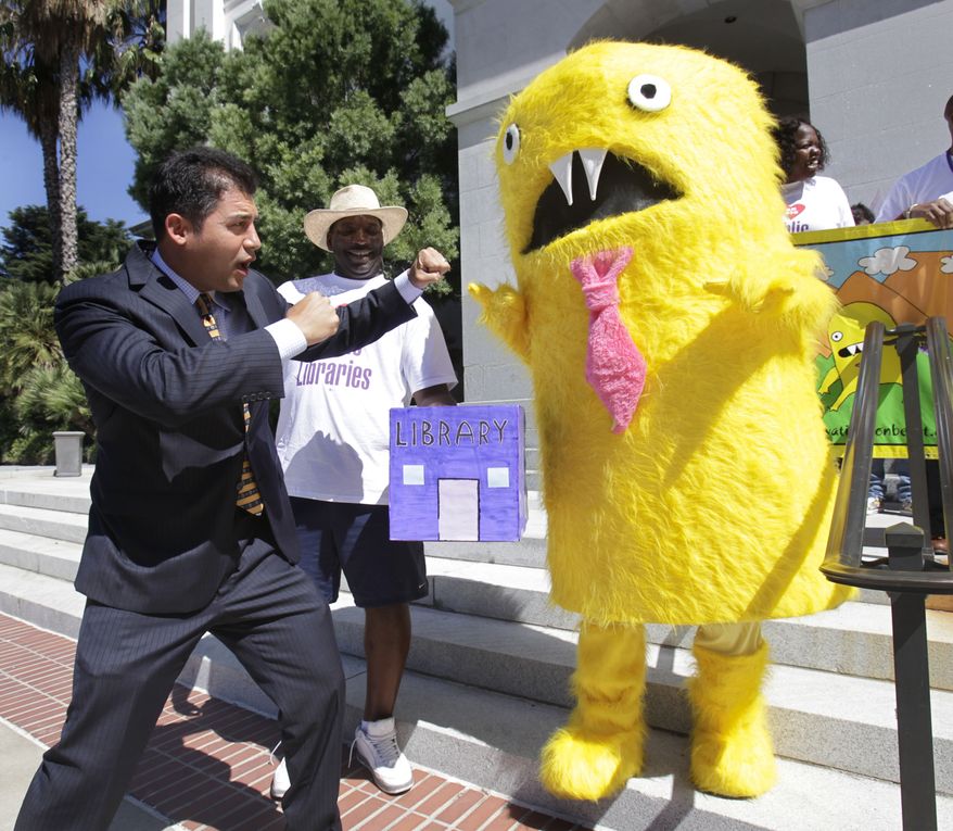 Assemblyman Das Williams, D-Santa Barbara, left, prepares to battle the "Privatization Beast," at a Capitol news conference to promote his measure that would place restrictions on the privatization of public libraries, in Sacramento, Calif., Monday, Aug. 22, 2011. If approved by the Senate and signed by the governor, Williams bill, AB438, would require contractors to prove they would save taxpayers money should they take over a library. It would also require the contracts be put out to competitive bidding and the winning companies would be subjected to financial and performance audits. (AP Photo/Rich Pedroncelli)