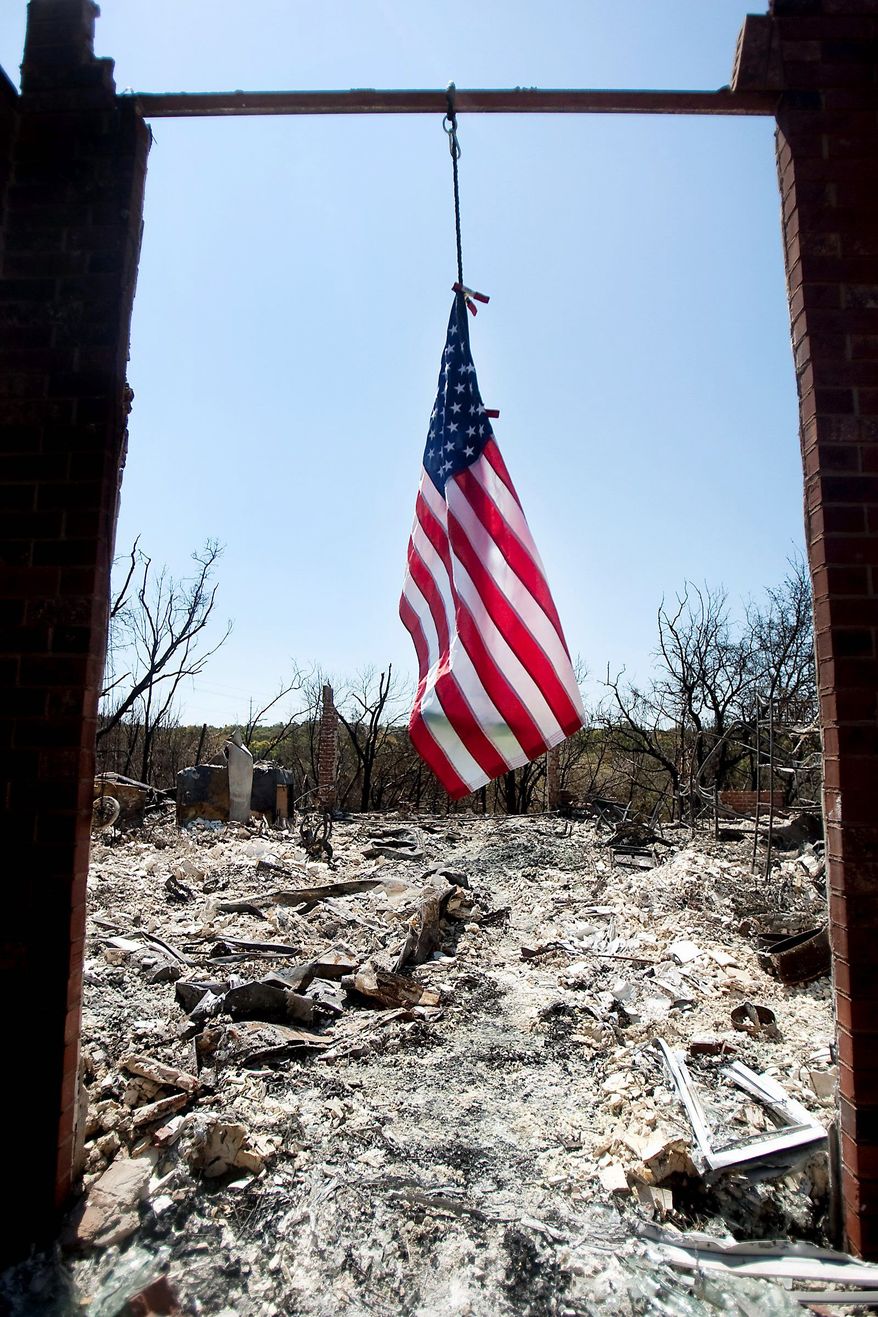 A flag hangs from the frame above the front door of a home on Medina River Way in Steiner Ranch in Austin, Texas, on Saturday. Texas is in the midst of one of its worst wildfire outbreaks in state history.