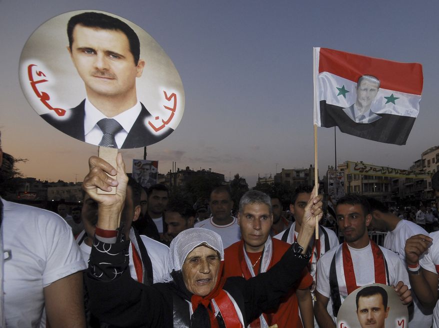 A pro-Syrian regime supporter shouts slogans while holding a portrait of Syrian President Bashar Assad with Arabic words that read "We all with you," during a rally on Sept. 11, 2011, in Damascus, Syria, to show support for Assad. (Associated Press)
