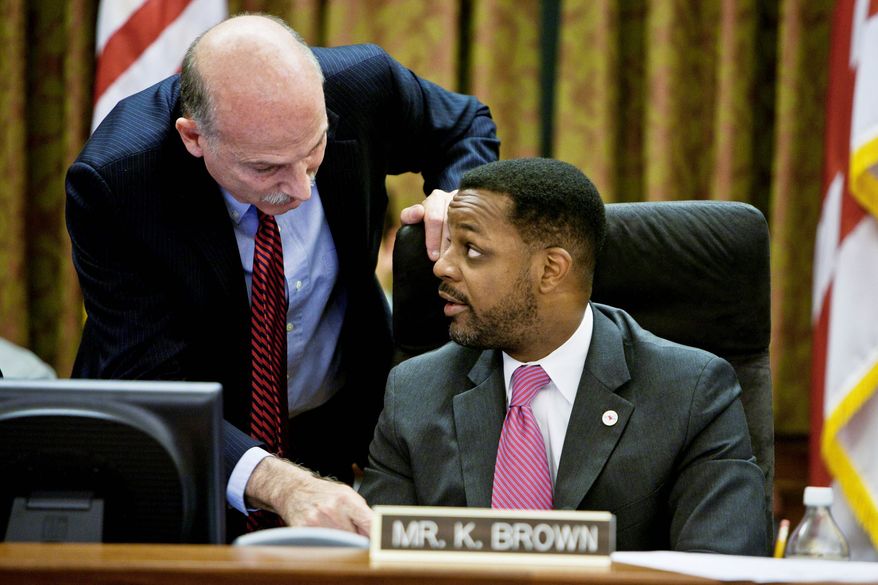 D.C. Council member Phil Mendelson confers with council Chairman Kwame R. Brown on Tuesday. Mr. Mendelson favored the income-tax increase; Mr. Brown opposed it. (T.J. Kirkpatrick/The Washington Times)