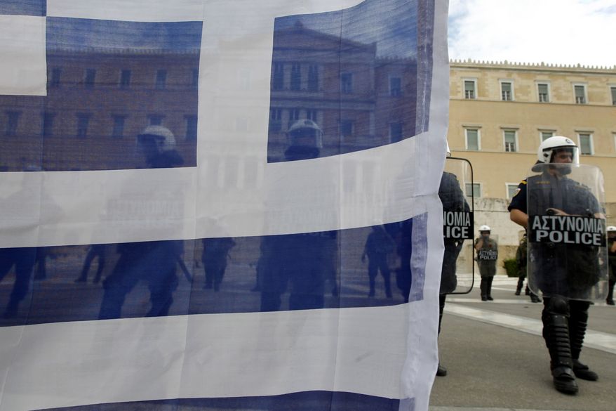Riot police stand guard outside the Greek parliament, seen through a Greek flag held by a protester, during a civil-servant protest in Athens on Tuesday, Oct. 11, 2011. (AP Photo/Petros Giannakouris)