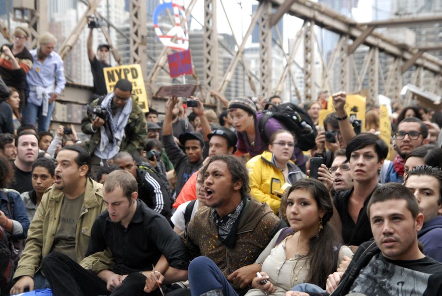 **FILE** Protesters sit with arms linked on New York's Brooklyn Bridge on Oct. 1, 2011, before police began making arrests during a march by Occupy Wall Street. (Associated Press)