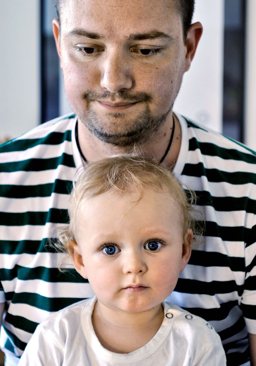 Henrik Holgersson sits with his son, Arvid, at their home in Stockholm. Mr. Holgersson has split Sweden's parental leave with his girlfriend and is spending eight months at home with their child. (Associated Press)