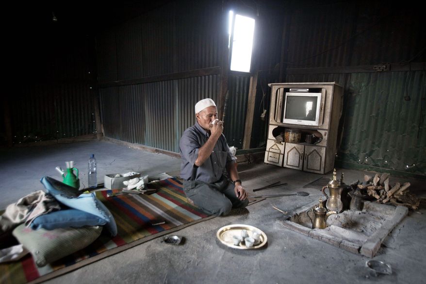 An Israeli Bedouin man drinks coffee in his village near the southern Israeli city of Beersheba, the Negev's main city. The nomadic people are clustered in impoverished towns and villages, many devoid of basic services. (Associated Press)