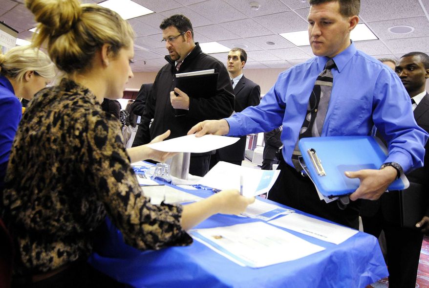 In this Nov. 2, 2011, photo, Clarence Turner of Little Canada, Minn., hands in his resume at the Minneapolis Career Fair held in Bloomington, Minn., where he was looking for a hotel audit job. (AP Photo/Jim Mone)