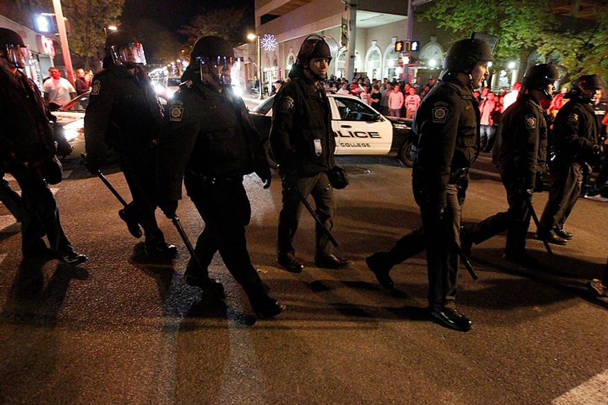 Police head across a street in State College, Pa., on Wednesday night, Nov. 9, 2011, as students gather after the Penn State board of trustees voted to fire football coach Joe Paterno and university President Graham Spanier. (AP Photo/Matt Rourke)