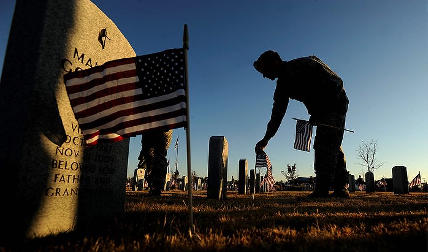 Staff Sgt. Tim Slusser puts a flag at one of the headstones at the Texas State Veterans Cemetary in Abilene, Texas, on Thursday, Nov. 10, 2011, in preparation for Veteran's Day on Friday. (AP Photo/Abilene Reporter-News, Tommy Metthe)