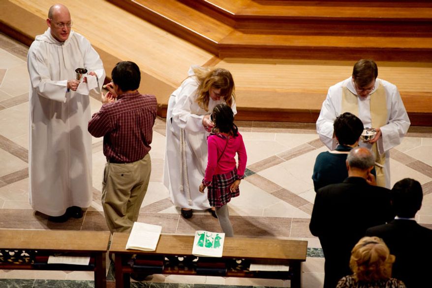 A young churchgoer receives communion, center, at National Cathedral before the Service of Holy Eucharist begins. (Andrew Harnik / The Washington Times)