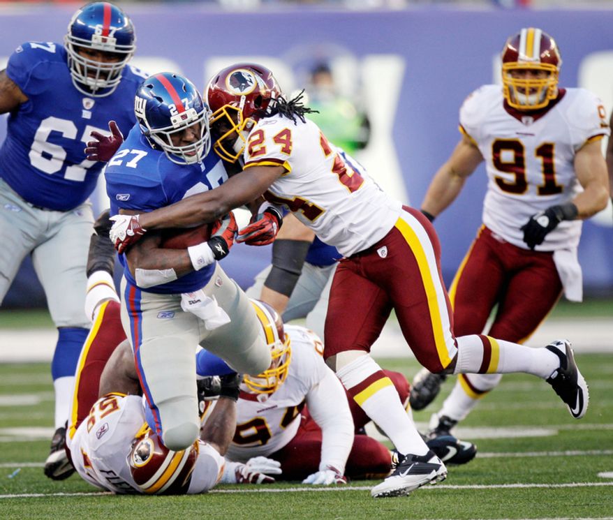 New York Giants' Brandon Jacobs, left, is tackled by Washington Redskins' DeJon Gomes during the third quarter. (AP Photo/Kathy Willens)