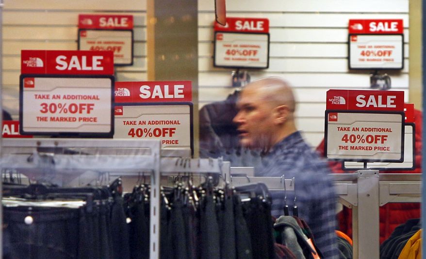 ** FILE ** Sale signs are displayed at a North Face store in Freeport, Maine, where a shopper browses the racks on Friday, Dec. 23, 2011. (AP Photo/Robert F. Bukaty, File)