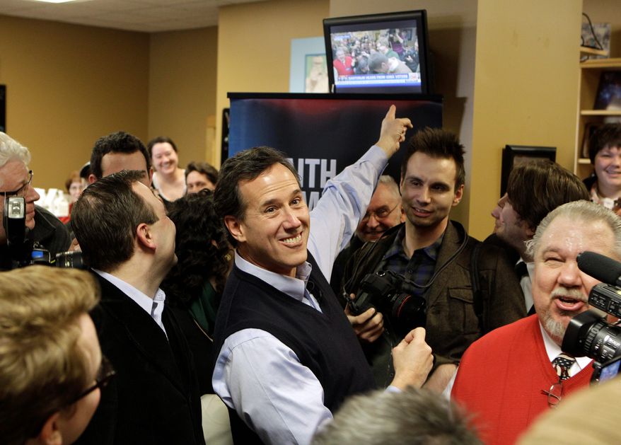 Republican presidential hopeful Rick Santorum points to a television showing his campaign stop Sunday at the Daily Grind coffee shop in Sioux City, Iowa. Mr. Santorum is enjoying a surge ahead of Tuesday's Iowa caucuses. (Associated Press)