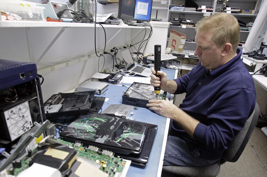 Technician Shawn Cable repairs a video game console Jan. 5, 2012, at the Laptops Plus computer store in Winter Park, Fla. (Associated Press)