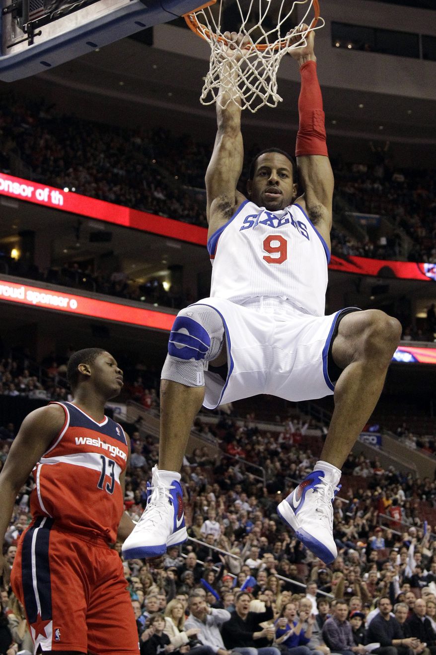 Philadelphia 76ers' Andre Iguodala hangs on the rim after dunking against Washington Wizards' Kevin Seraphin in the second half, Friday, Jan. 13, 2012, in Philadelphia. Philadelphia won 120-89. (AP Photo/Matt Slocum)