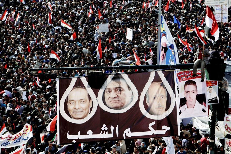 Egyptian protesters hold a large banner depicting Gen. Hussein Tantawi, left, former President Hosni Mubarak, center, and former interior minister Habib al-Adly in nooses with Arabic writing that reads, "The peoples rule," in Tahrir Square during a rally to mark the one year anniversary of the uprising that ousted President Hosni Mubarak in Cairo, Egypt, Wednesday, Jan. 25, 2012. Tens of thousands of Egyptians rallied Wednesday to mark the first anniversary of the country's 2011 uprising, with liberals and Islamists gathering on different sides of Cairo's Tahrir Square in a reflection of the deep political divides that emerged in the year since the downfall of longtime leader Hosni Mubarak. The graffiti at right, in Arabic, reads, "freedom," and "down with the military rule."(AP Photo/Muhammed Muheisen)