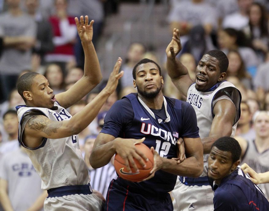 Georgetown's Greg Whittington, left, and Henry Sims, top right, defend Connecticut's Andre Drummon. (AP Photo/Haraz Ghanbari)