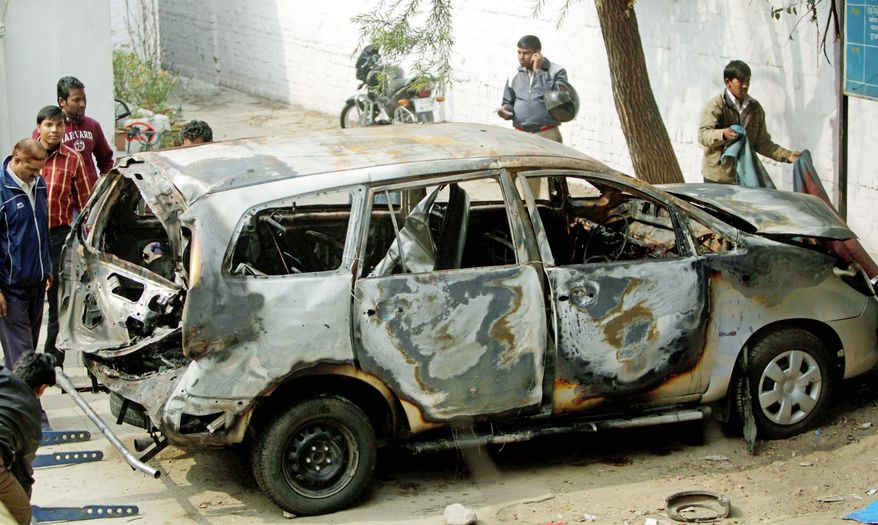 Indian police officers check out an Israeli diplomat's car that was damaged in an explosion Tuesday in New Delhi. Indian investigators suspect that a motorcycle rider attached the bomb to the car. (Associated Press)
