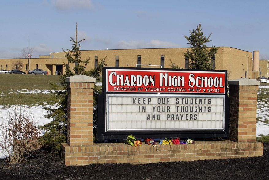 Bouquets of flowers sit on the sign in front of the high school in Chardon, Ohio, Tuesday, Feb. 28, 2012. A gunman opened fire inside the school's cafeteria at the start of the school day Monday. (AP Photo/Mark Duncan)