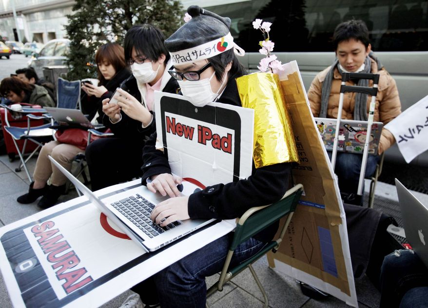 Ryo Takahashi wearing a samurai wig browses internet as he and others wait in a queue to buy a new iPad outside an Apple Store in Tokyo, Thursday, March 15, 2012, one day before the the new iPad goes on sale Friday. (AP Photo/Shizuo Kambayashi)