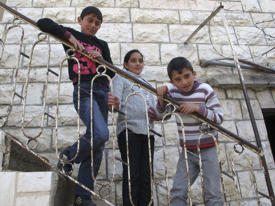 ** FILE ** In this March 12, 2012, photograph, Mahmoud al-Alami, 10, left, stands in front of his home with his cousin Farah, center, and brother Mamoun in Beit Umar, West Bank. (AP Photo/Diaa Hadid)