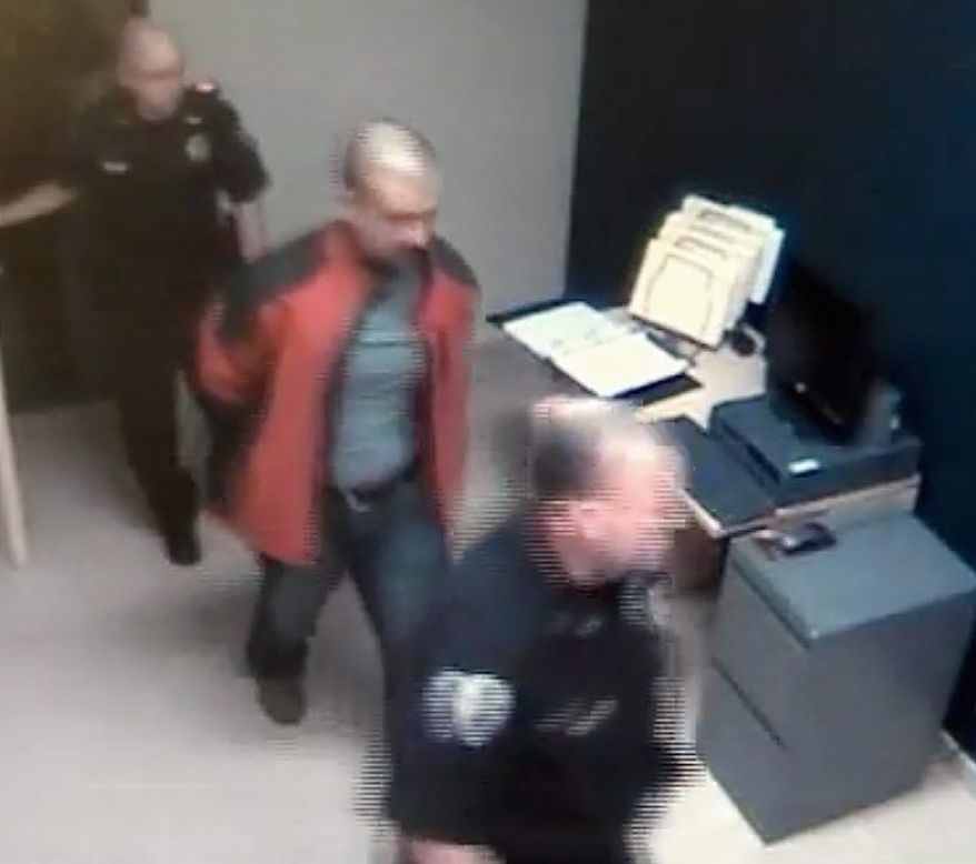 ** FILE ** George Zimmerman is escorted into the Sanford, Fla., police station in handcuffs the night he fatally shot Trayvon Martin. (Associated Press)