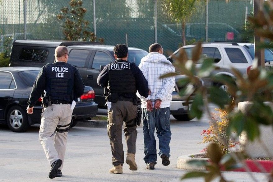 **FILE** Immigration and Customs Enforcement (ICE) agents take a suspect into custody as part of a nationwide immigration sweep in Chula Vista, Calif., on March 30, 2012. (Associated Press)