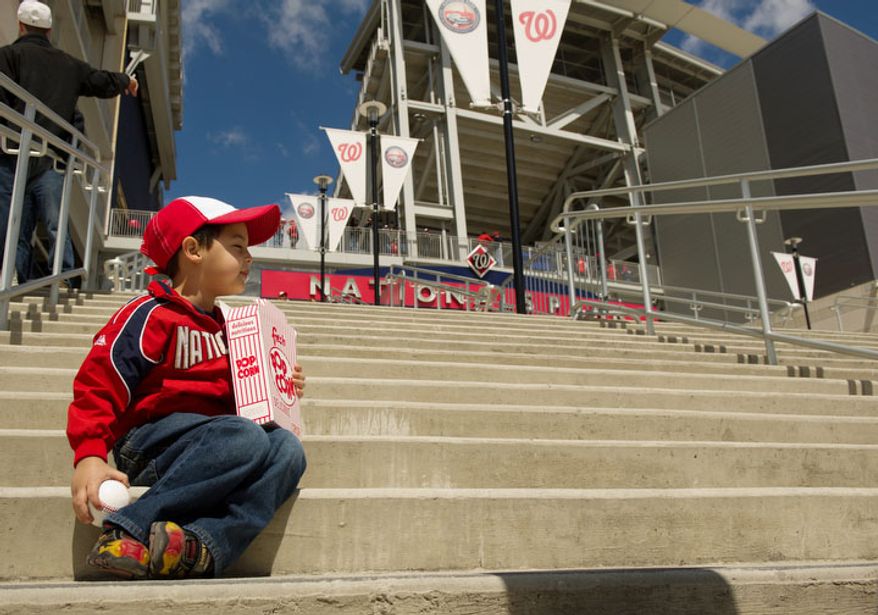 Ethan Martinez, 3, of Reston, Va., sits on steps leading into Nationals Park. (Andrew Harnik/The Washington Times)