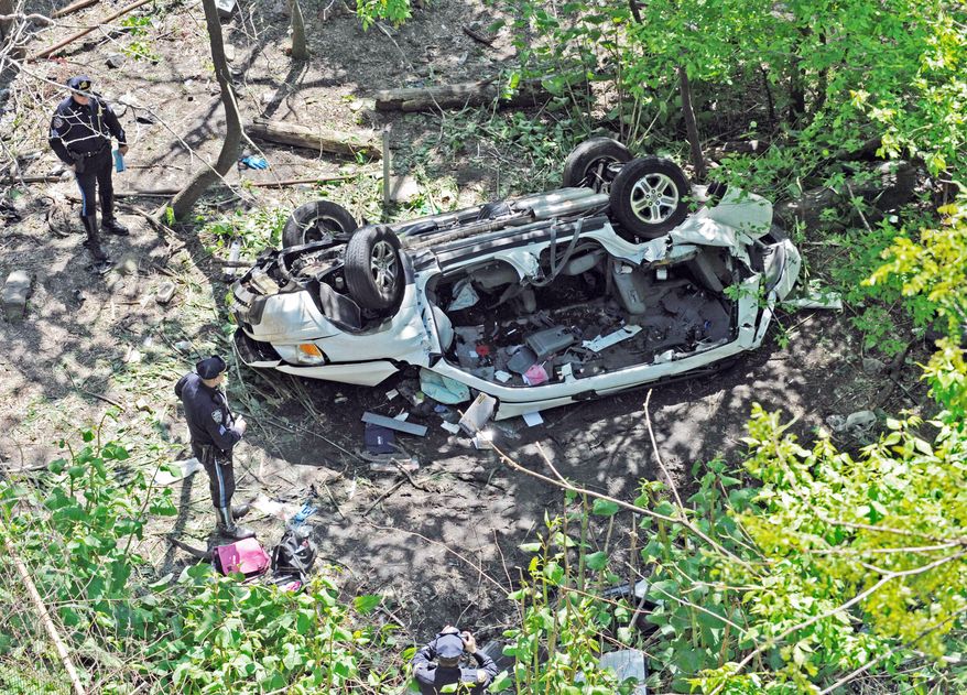 Police investigate the destroyed van that plunged over the Bronx River Parkway on Sunday in New York. Authorities say the out-of-control van plunged off a roadway near the Bronx Zoo, killing seven people, including three children. (Associated Press)