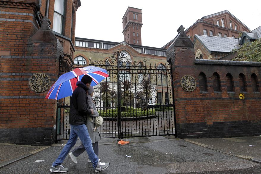 Pedestrians on Sunday, April 29, 2012, pass gated residential flats in Bow in east London, where the Defense Ministry has warned residents that surface-to-air missiles could be stationed on the rooftop during the London Olympics. (AP Photo/Sang Tan)