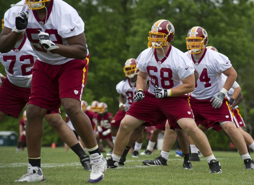 Tom Compton, center, # 68, an offensive tackle drafted from South Dakota, goes through stretching exercises at Redskins Park. (Barbara L. Salisbury/The Washington Times)