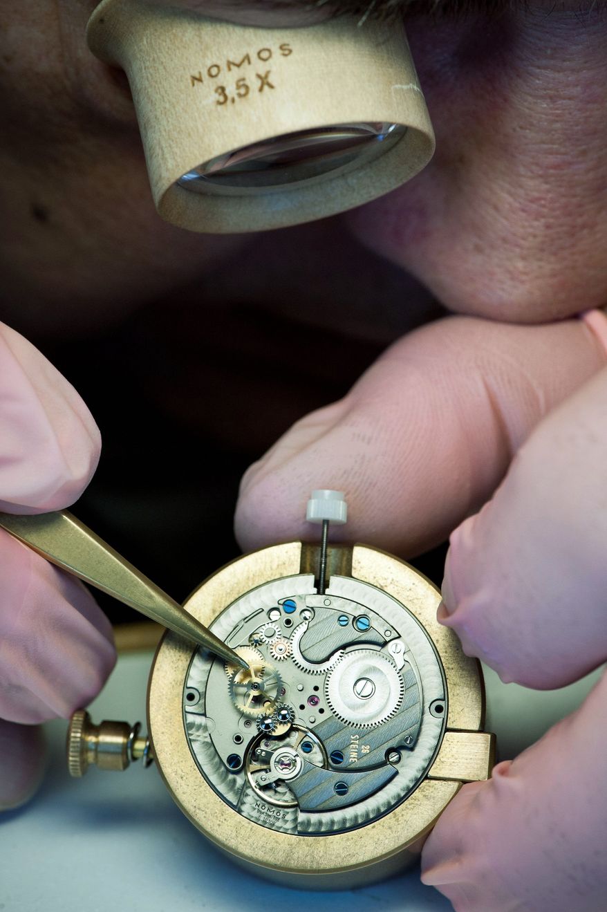A watchmaker for Nomos assembles a watch in Glashutte, Germany. At least 50 percent of the timekeeping movement must be made here by hand. The watches sell from $1,315 to $5,000. (Christian Burkert/Special to The Washington Times)