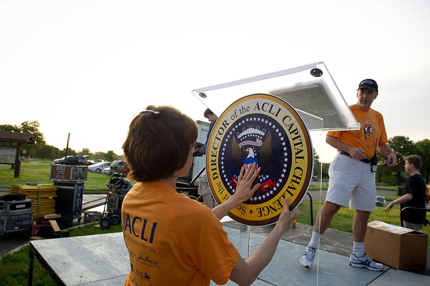 Susan Debad, of Ijamsville, Md., puts up a sign on the podium as she and others prepare for the ACLI Capital Challenge at Anacostia Park in Washington, D.C., Wednesday, May 16, 2012. This is the 31st running of the three-mile race where members of Congress, national media outlets and locals take part in this fundraising event in the early morning hours along the water of the Anacostia River. (Rod Lamkey Jr/The Washington Times)