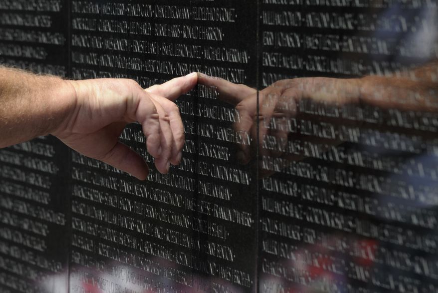 A visitor to the Vietnam Veterans Memorial touches the name of a fallen soldier etched on the wall of the memorial in Washington, Friday, May 25, 2012. (AP Photo/Susan Walsh)