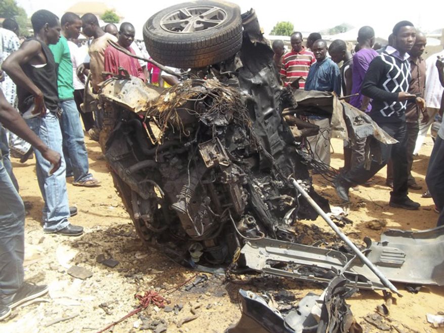 People gather around a car used by a suicide bomber following an explosion in a church compound in Bauchi, Nigeria, on Sunday, June 3, 2012. (AP Photo/Shehu Saulawa)
