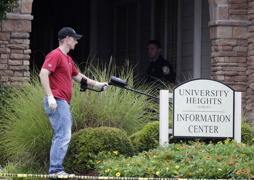 An investigator uses a metal detector to search for evidence at the scene of an overnight shooting at an apartment complex in Auburn, Ala., on Sunday, June 10, 2012. (AP Photo/David Goldman)