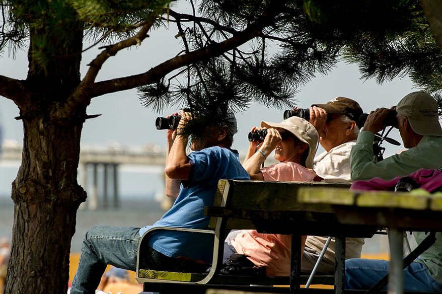 Wayne Sterling (from left) and his wife, Phyllis, both of Bridgeville, Del., and John Elliott of Queenstown, Md., watch June 13, 2012, through binoculars as tall ships pass under the Chesapeake Bay Bridge en route to the Inner Harbor in Baltimore for a bicentennial commemoration of the War of 1812. The week-long "Star-Spangled Sailabration" includes free tours of the ships, waterside festivities, an air show featuring the Blue Angels and the world premiere of "Overture for 2012," composed by Philip Glass. (Andrew Harnik/The Washington Times)