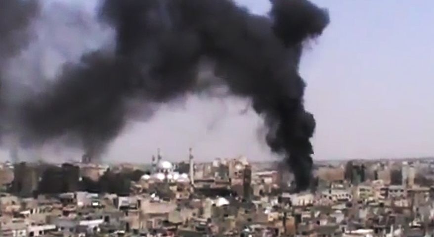 This image made from amateur video, released by the Shaam News Network and accessed on Monday, June 18, 2012, purports to show black smoke rising from buildings in Homs, Syria. (AP Photo/Shaam News Network via AP Video)