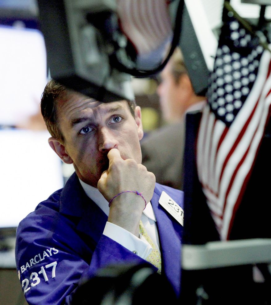 Specialist Christopher Trotta works on the floor of the New York Stock Exchange Monday. Stocks fell in both Europe and the U.S. (Associated Press)