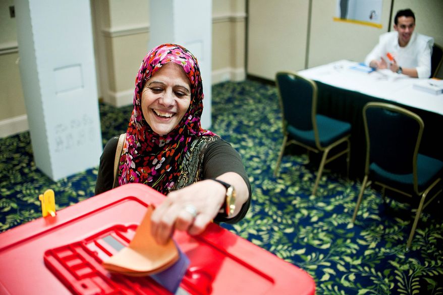 Teffaha Abeidi, 58, of Fairfax casts her ballot at the Holiday Inn in Arlington on Tuesday, the first time the native of Libya had voted in her lifetime. "I'm so excited, my legs are still shaking," she said. (Ryan M.L. Young/The Washington Times)