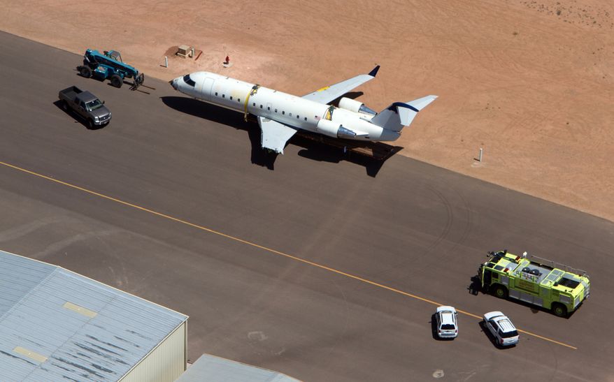 A SkyWest regional jet sits on the tarmac on the opposite end of the St. George Municipal Airport Tuesday, July 17, 2012. A SkyWest Airlines employee wanted in a murder case attempted to steal a passenger plane, then shot himself in the head after crashing the aircraft in a nearby parking lot, officials said Tuesday. Brian Hedglin, 40, scaled a razor wire fence at the St. George Municipal Airport early Tuesday, then boarded the 50-passenger SkyWest jet while the airport was closed, St. George city spokesman Marc Mortenson said. (AP Photo/The Spectrum, Jud Burkett)