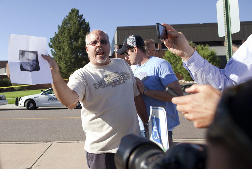 Tom Sullivan holds a photograph of his son, Alex, outside Gateway High School in Aurora, Colo., on July 20, 2012, as he pleads with the media to help him find his son. Alex Sullivan was celebrating his 27th birthday by attending midnight premiere of the Batman movie Friday night. A gunman wearing a gas mask set off an unknown gas and fired into the crowded movie theater killing 12 people and injuring at least 50 others, authorities said. (Associated Press)