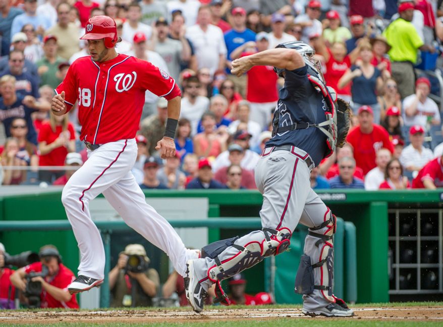 Nationals' Michael Morse scores on a Danny Espinosa RBI single in the bottom of the third inning as Braves catcher Brian McCann can't make the tag. (Rod Lamkey Jr./The Washington Times)