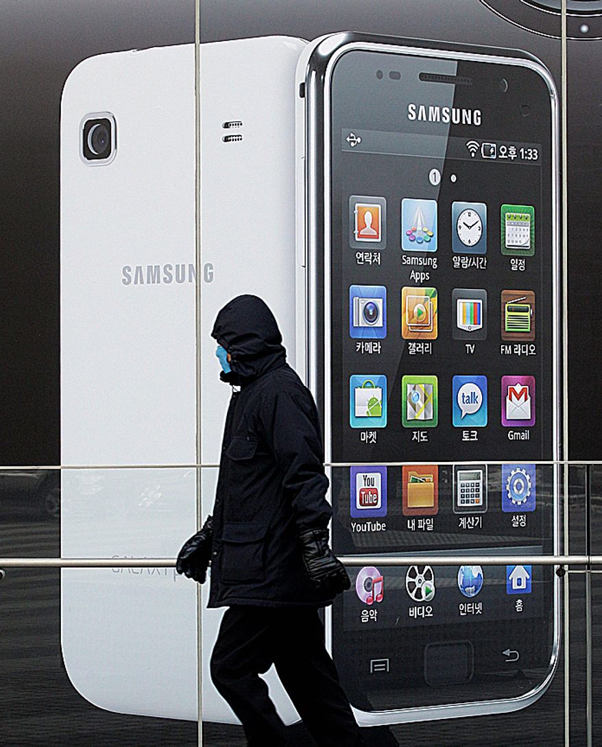 ** FILE ** A man walks by signs advertising Samsung Electronics Co.'s smartphone in Seoul on Jan. 28, 2011. (Associated Press)