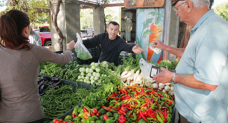 Richard Wolk buys fresh produce from Ching Thao at the Vineyard Farmers Market in California, a state that is leading the way in direct-sales markets. (Associated Press)
